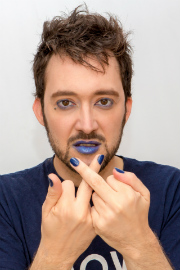 Photo de Pouhiou avec les yeux, les lèvres et les ongles peints en bleu.